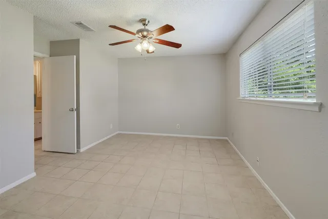 an empty room with windows and fan