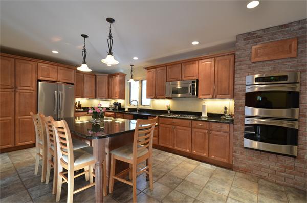 47 Pierpont Road Dudley, MA 01571 - Photo 8 of 30 a kitchen with stainless steel appliances granite countertop a stove top oven a sink dishwasher a dining table and chairs with wooden cabinets