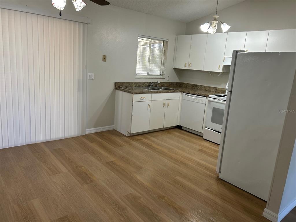 301 Oak Track Loop Ocala, FL 34472 - Photo 6 of 14 a kitchen with granite countertop a refrigerator a sink dishwasher a stove and white cabinets with wooden floor