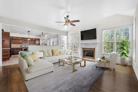 a view of a livingroom with a fireplace a ceiling fan and windows