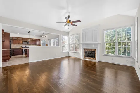 an empty room with wooden floor fireplace and windows