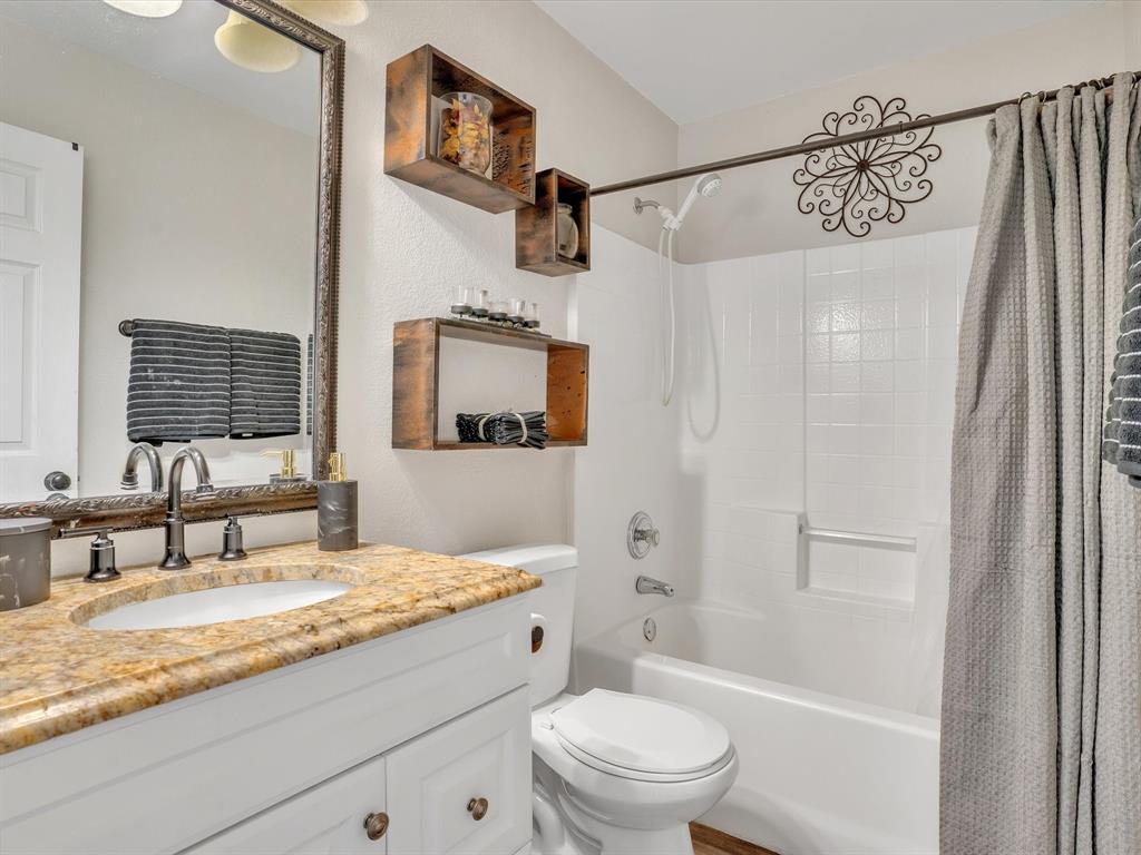 15067 Meadow Ridge Court Nevada, TX 75173 - Photo 16 of 39 a bathroom with a granite countertop sink a mirror a bathtub and shower