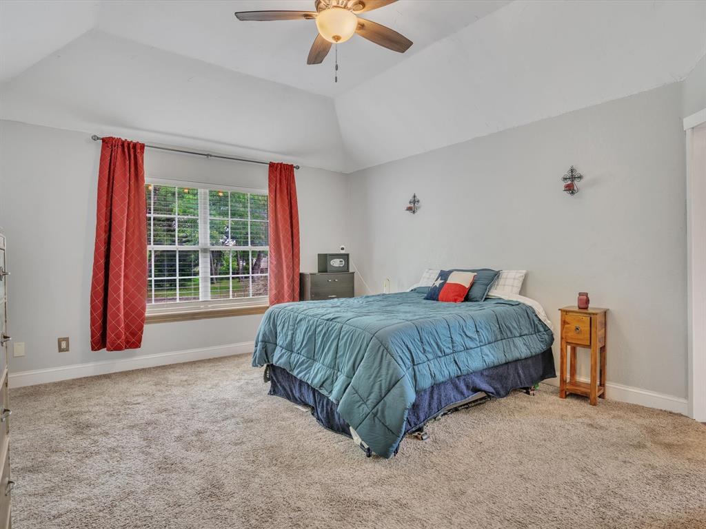 15067 Meadow Ridge Court Nevada, TX 75173 - Photo 25 of 39 a spacious bedroom with a bed and a chandelier