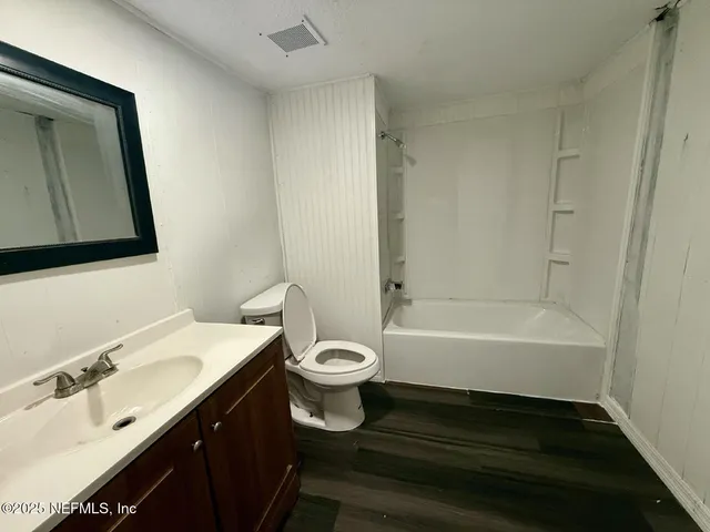 a bathroom with a bathtub sink vanity mirror and toilet