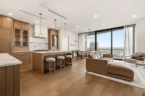 a living room with furniture kitchen area and large windows