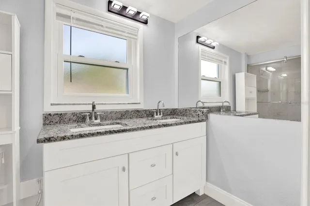 a bathroom with a granite countertop sink and a mirror
