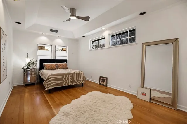 a bedroom with a bed and dresser with wooden floor