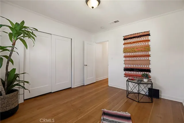 a view of an empty room with kitchen and hardwood floor