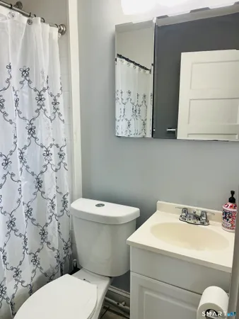 a white toilet sitting next to a white sink and vanity