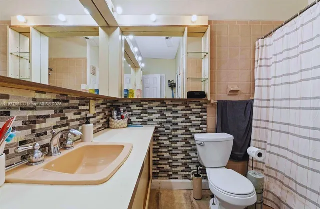 a bathroom with a sink a toilet a mirror and shower