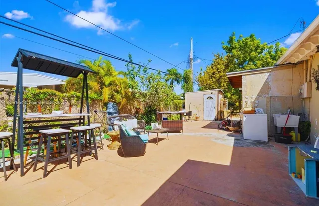 a view of a patio with table and chairs potted plants and a large tree