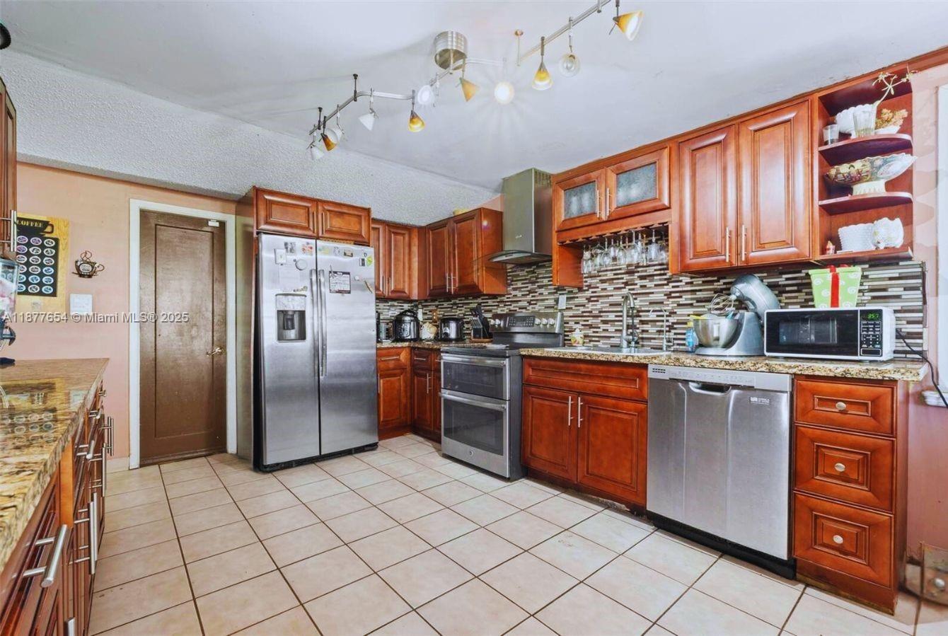 8571 Southwest 30th Street Miami, FL 33155 - Photo 5 of 15 a kitchen with stainless steel appliances granite countertop a stove refrigerator and a sink