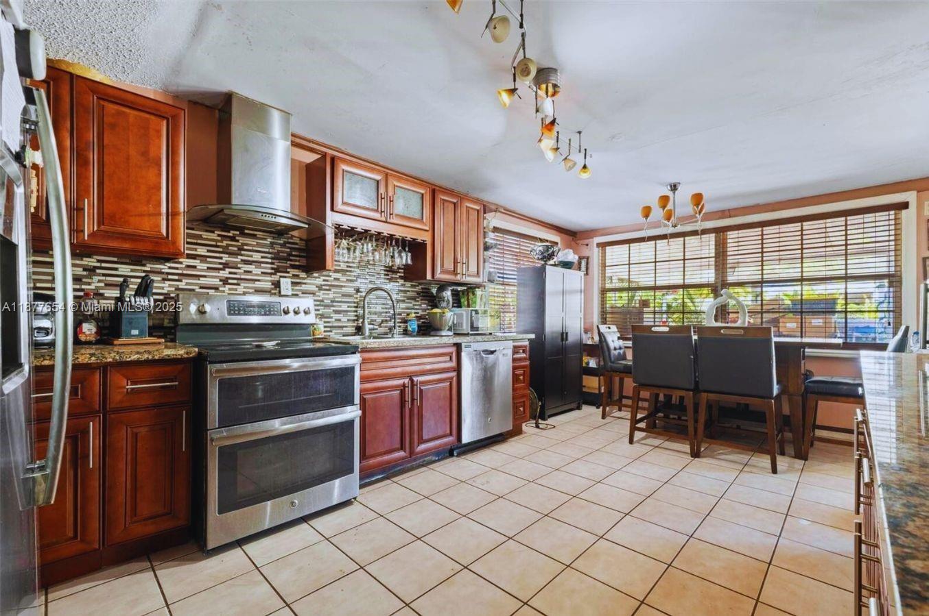 8571 Southwest 30th Street Miami, FL 33155 - Photo 6 of 15 a kitchen with stainless steel appliances granite countertop a stove a sink dishwasher and a chair with granite countertops
