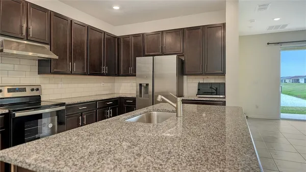 a kitchen with kitchen island granite countertop a stove a sink a refrigerator and cabinets