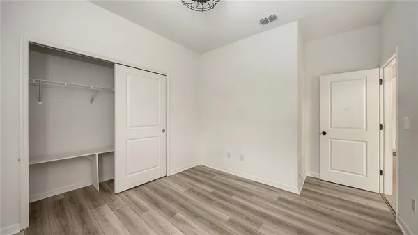 an empty room with wooden floor and closet