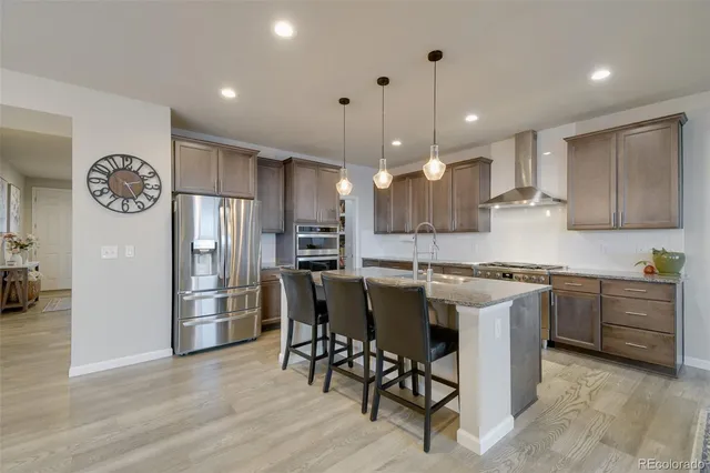 a kitchen with a refrigerator a stove top oven a sink dishwasher with a dining table and chairs