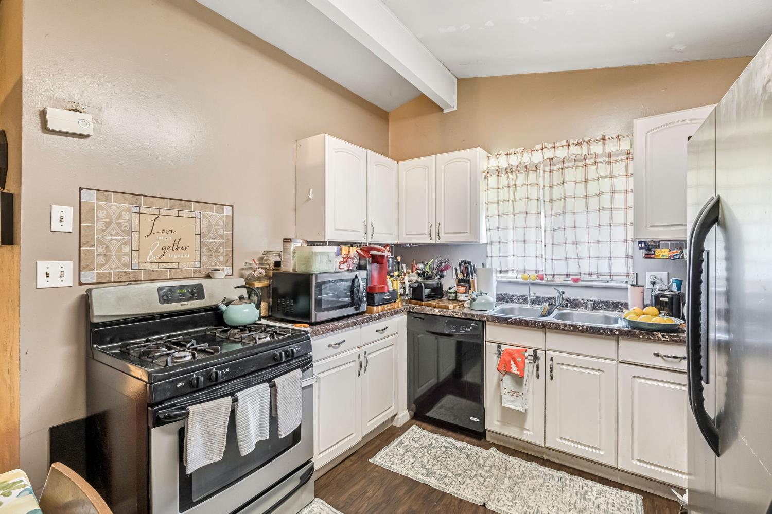 1205 Rogers Street Madera, CA 93638 - Photo 16 of 23 a kitchen with a stove a sink dishwasher and white cabinets with wooden floor