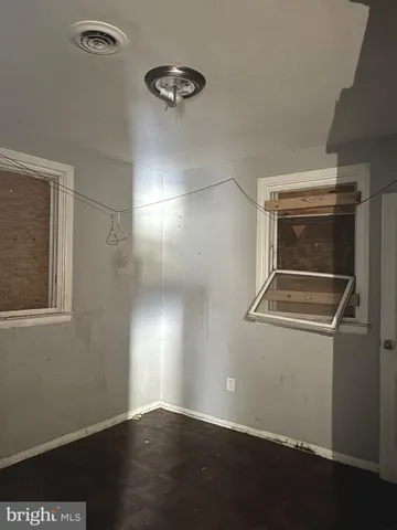 an empty room with wooden floor cabinet and windows