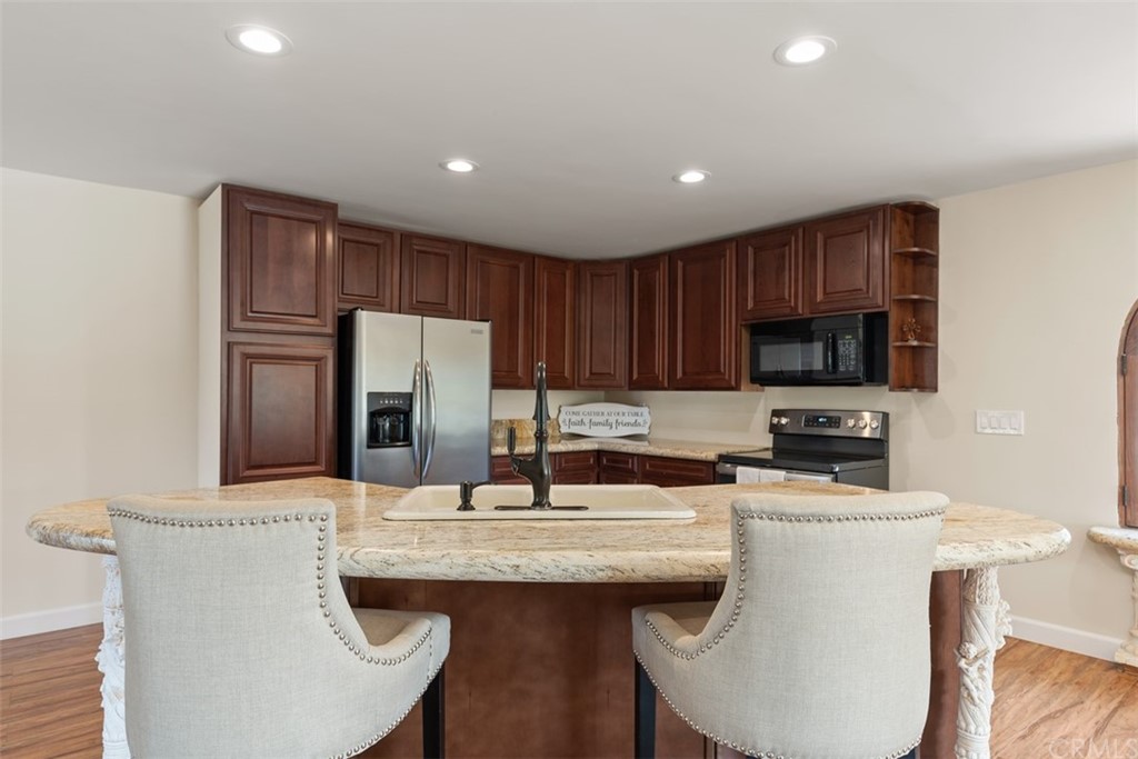 29752 Ivy Glenn Drive Laguna Niguel, CA 92677 - Photo 15 of 36 a kitchen with stainless steel appliances kitchen island granite countertop a sink a stove a refrigerator cabinets and chairs