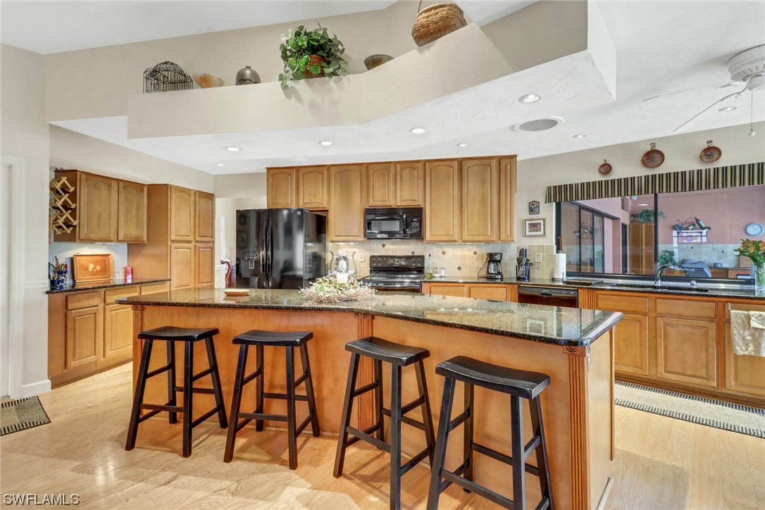 14813 Soaring Eagle Court Fort Myers, FL 33912 - Photo 3 of 19 a kitchen with stainless steel appliances granite countertop a table chairs sink refrigerator and cabinets