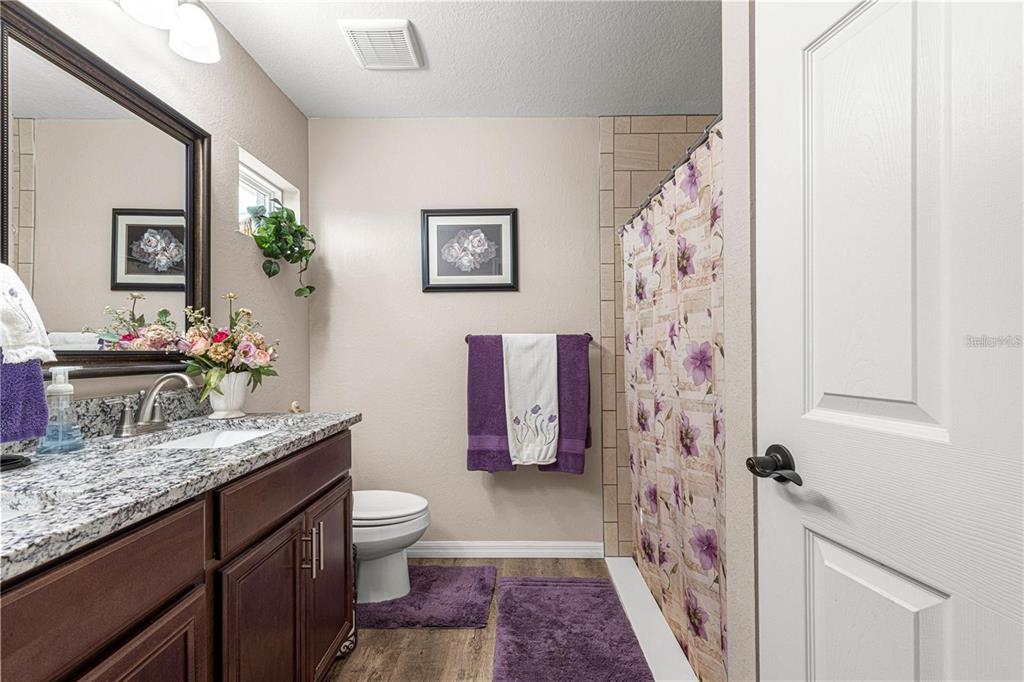 13057 Southwest 85th Circle Ocala, FL 34473 - Photo 19 of 32 a bathroom with a granite countertop sink a toilet and shower curtain