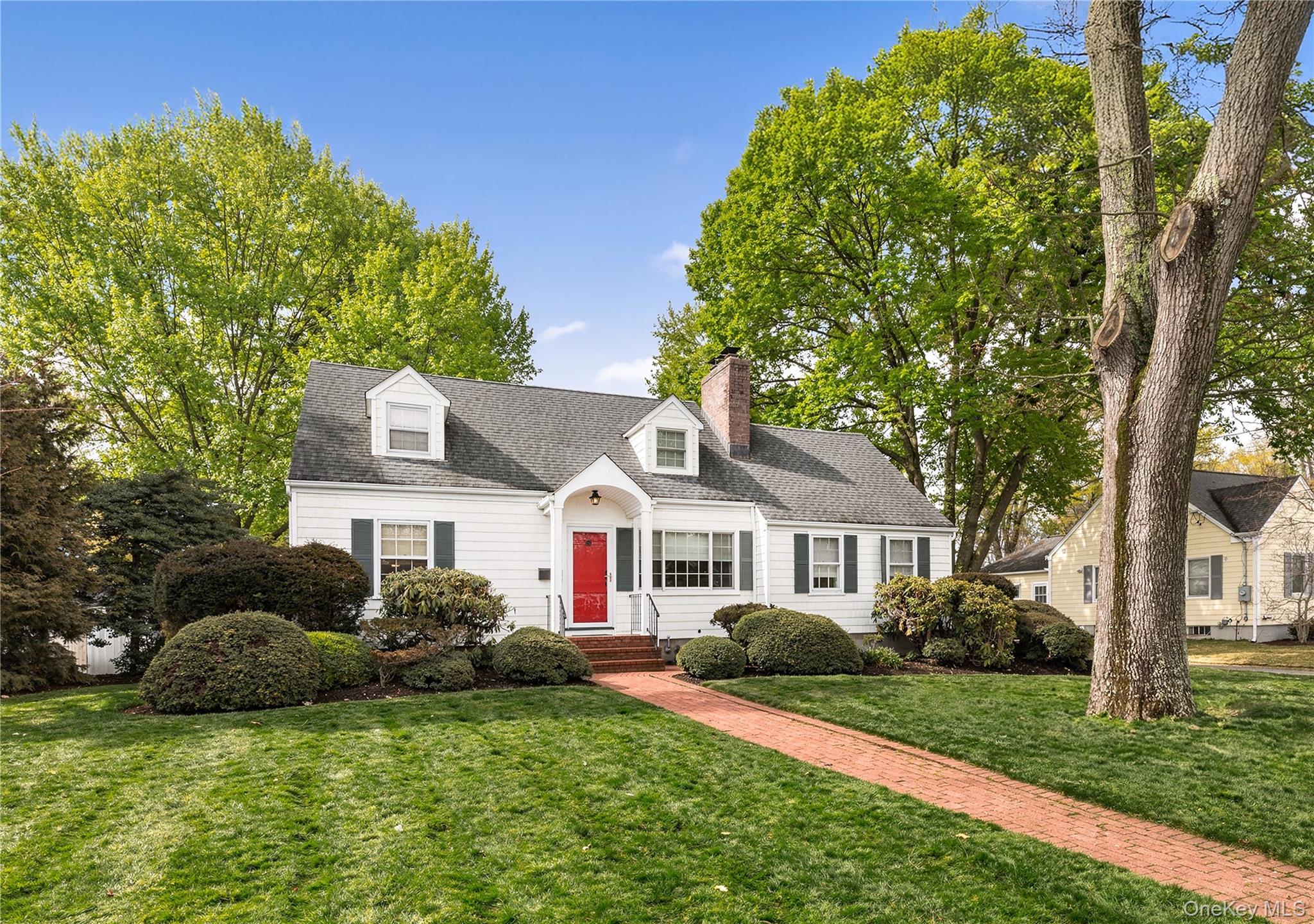 a front view of a house with a garden and trees