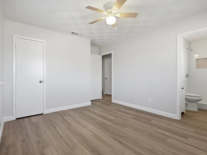 an empty room with wooden floor and a ceiling fan