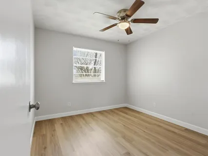 an empty room with a window and a ceiling fan