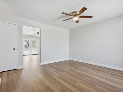 a view of empty room with wooden floor and ceiling fan