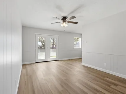an empty room with wooden floor and windows