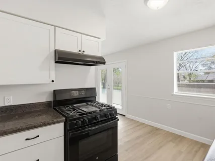 a kitchen with granite countertop a stove and a wooden cabinets