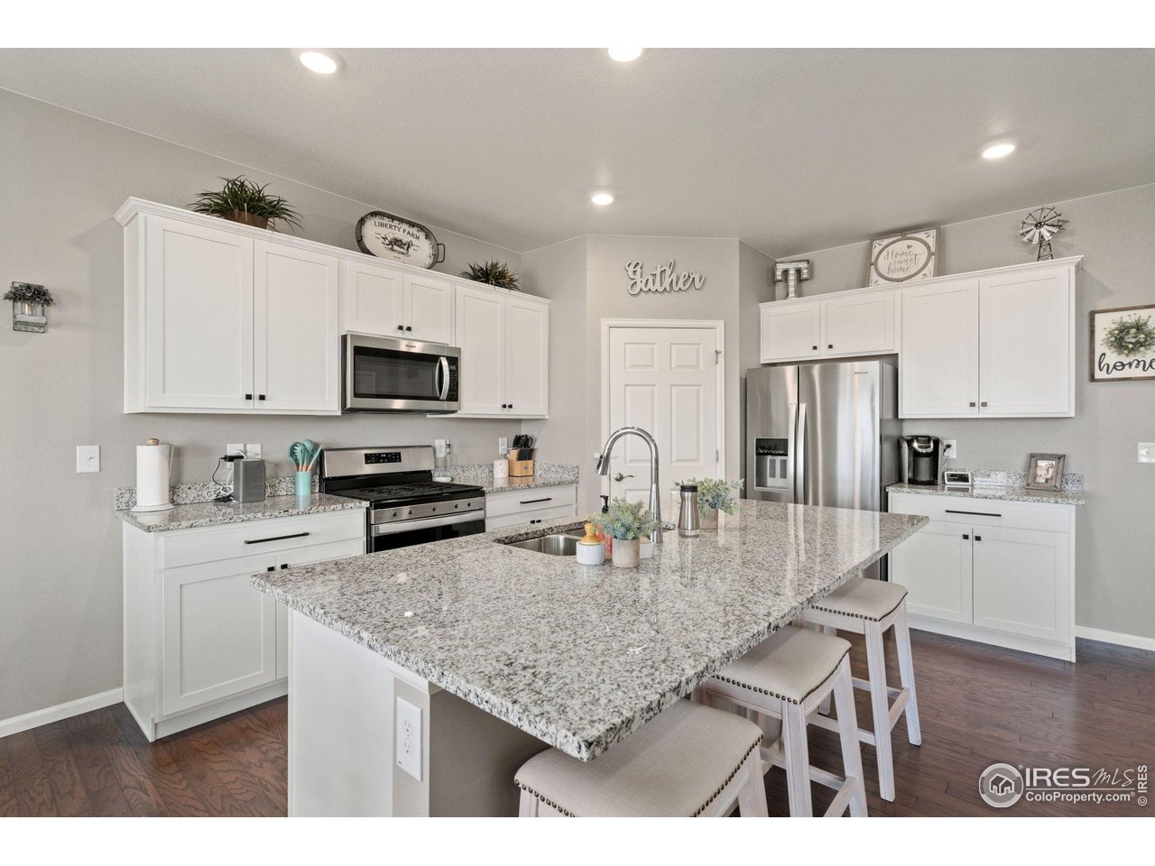 176 Haymaker Lane Severance, CO 80550 - Photo 10 of 25 a kitchen with white cabinets and stainless steel appliances