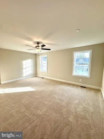 an empty room with windows and chandelier fan