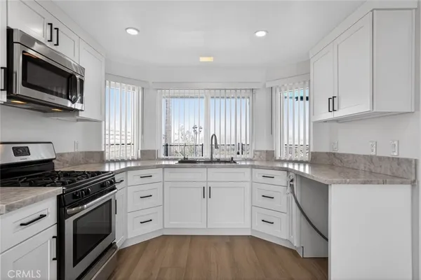 a kitchen with granite countertop white cabinets and stainless steel appliances