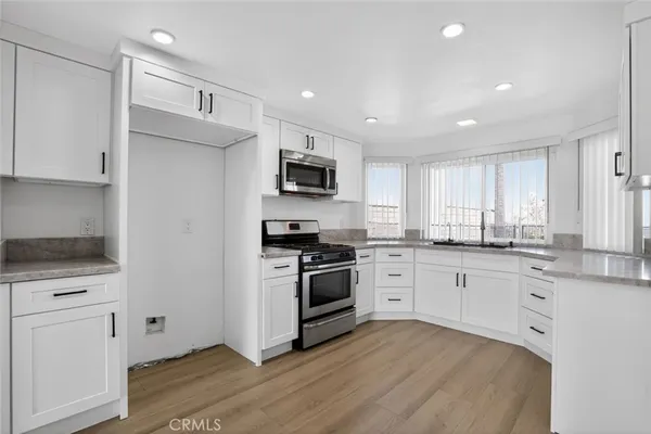 a kitchen with granite countertop white cabinets and stainless steel appliances