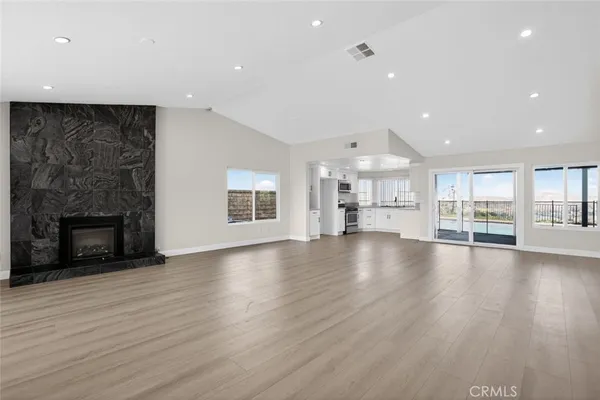 a view of an empty room with wooden floor and a fireplace