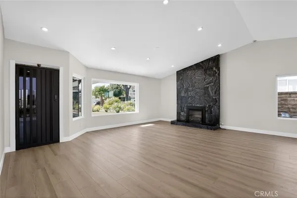 an empty room with windows and fireplace
