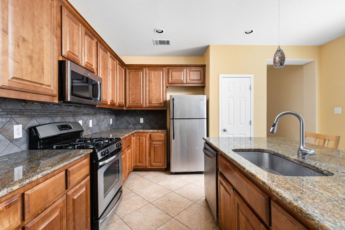 7109 Via Correto Drive Austin, TX 78749 - Photo 17 of 40 a kitchen with stainless steel appliances granite countertop a stove a sink dishwasher a refrigerator and a microwave