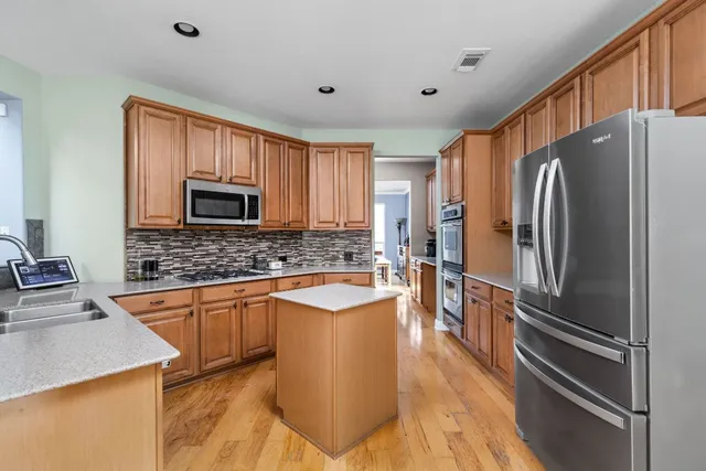 a kitchen with stainless steel appliances granite countertop a sink a stove and a wooden floors