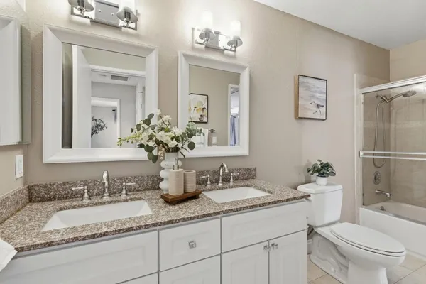 a bathroom with a granite countertop sink double mirror and a toilet