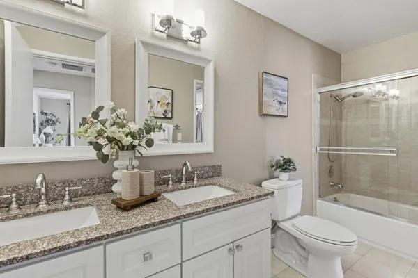 a bathroom with a granite countertop sink a toilet a mirror and shower