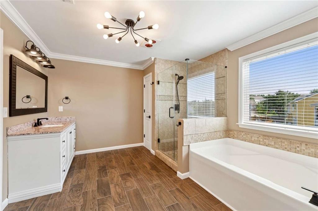 4510 Trailmaster Circle Cumming, GA 30028 - Photo 31 of 49 a bathroom with a bathtub a sink and a large mirror