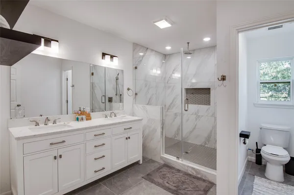 a bathroom with a double vanity sink toilet and shower