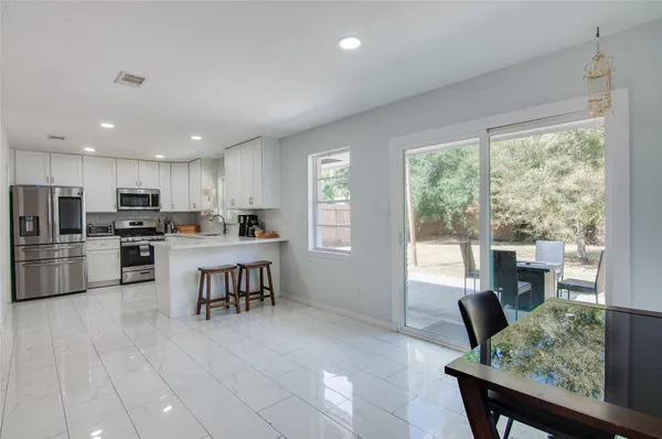 a open kitchen with kitchen island a large window in it and stainless steel appliances