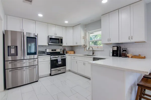 a kitchen with granite countertop white cabinets and stainless steel appliances
