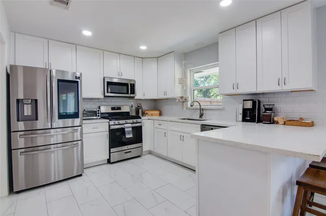 a kitchen with white cabinets and sink