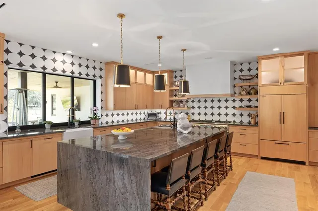 a kitchen with granite countertop a sink a counter top space dining table and stainless steel appliances