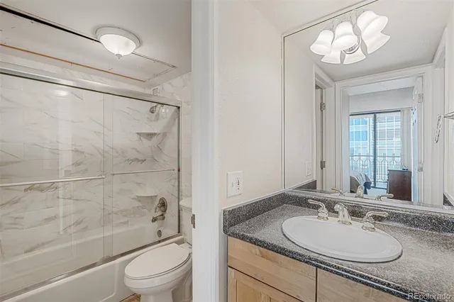 a bathroom with a granite countertop sink toilet mirror and shower