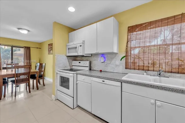 a kitchen with granite countertop white cabinets and white appliances