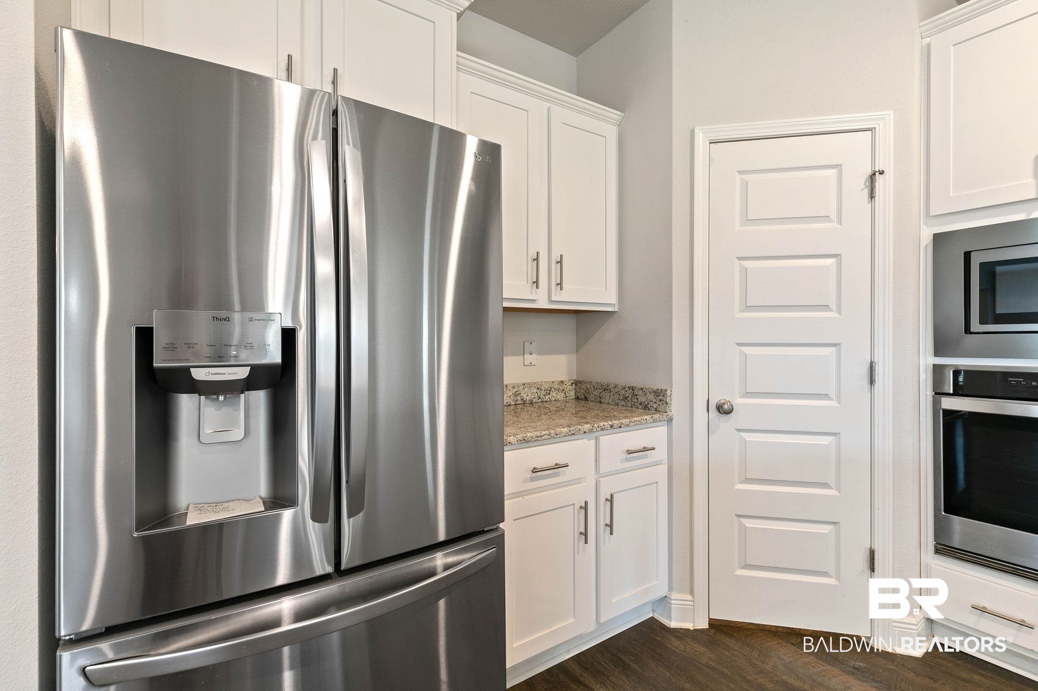 9448 Amethyst Drive Daphne, AL 36526 - Photo 21 of 61 Kitchen featuring stainless steel appliances, white cabinets, light stone countertops, and dark wood finished floors